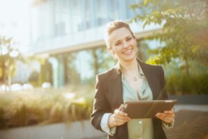 A businesswoman standing outside of a building holding an iPad by NorCal Roofing & Gutters