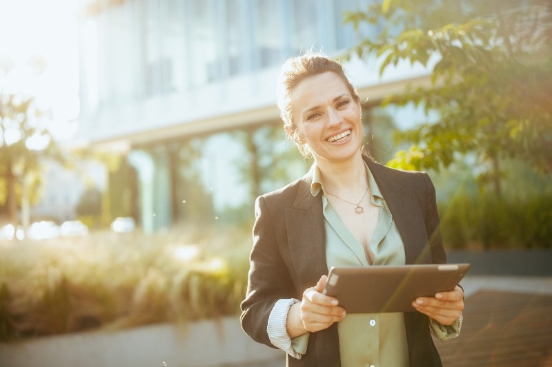 A businesswoman standing outside of a building holding an iPad by NorCal Roofing & Gutters