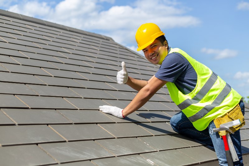 A man in a hard hat and vest on top of a roof giving the thumbs up by NorCal Roofing & Gutters