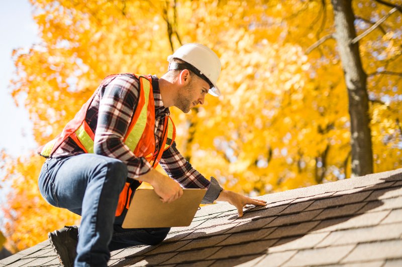 A man wearing a hard hat on a roof performing an inspection by NorCal Roofing & Gutters