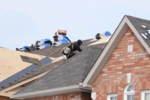Someone on a roof replacing the shingles by NorCal Roofing & Gutters