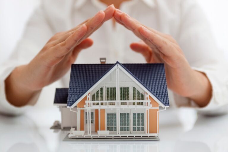 Small toy house with a person holding their hands over it by NorCal Roofing & Gutters