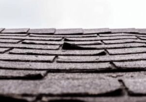 A close-up of roofing shingles that are separating from a roof by NorCal Roofing & Gutters