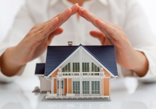 Small toy house with a person holding their hands over it by NorCal Roofing & Gutters