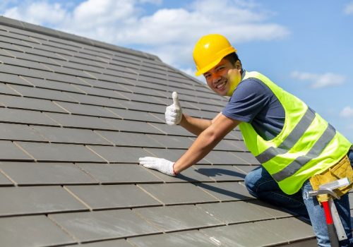 A man in a hard hat and vest on top of a roof giving the thumbs up by NorCal Roofing & Gutters