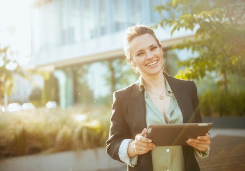 A businesswoman standing outside of a building holding an iPad by NorCal Roofing & Gutters