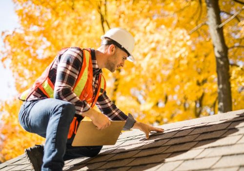 A man wearing a hard hat on a roof performing an inspection by NorCal Roofing & Gutters